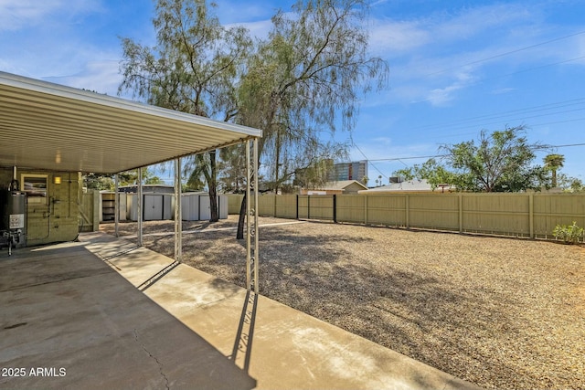 view of yard with a patio area, an attached carport, an outbuilding, a fenced backyard, and a storage unit