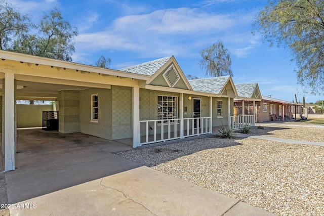 view of front of property featuring a shingled roof, concrete driveway, a porch, and a carport
