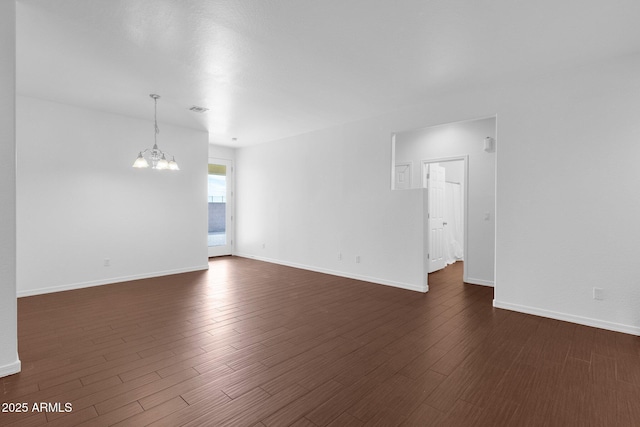 unfurnished room featuring an inviting chandelier and dark wood-type flooring