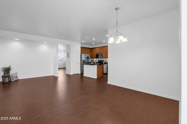 unfurnished living room featuring dark wood-type flooring and an inviting chandelier