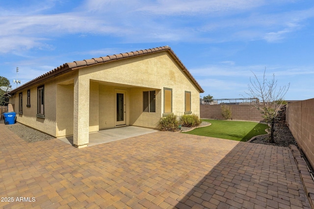 back of property with a lawn and a patio area