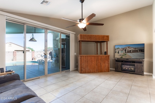 living room with ceiling fan, light tile patterned floors, and vaulted ceiling