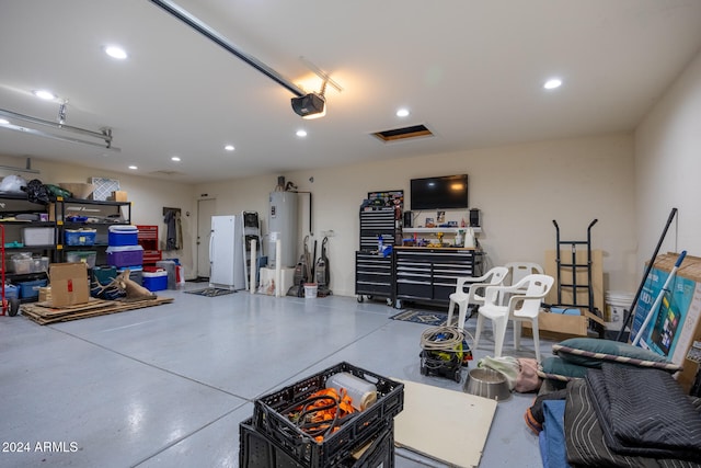 garage featuring a garage door opener, white refrigerator, and electric water heater