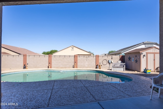 view of pool with a shed and a patio