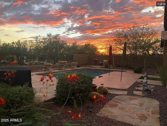 pool at dusk featuring a patio