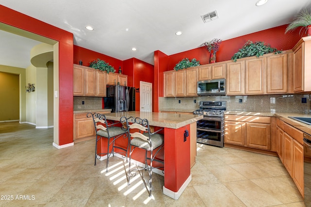 kitchen with sink, a kitchen breakfast bar, decorative backsplash, a center island, and black appliances