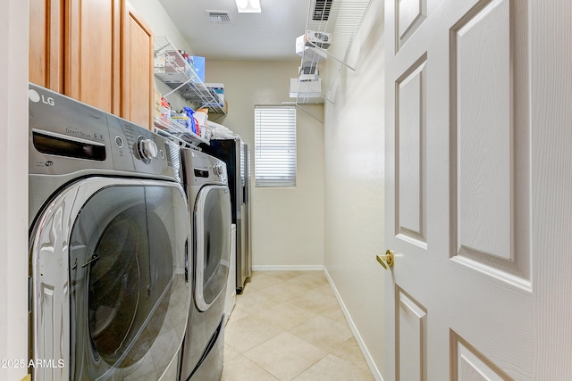 washroom featuring light tile patterned floors, washer and clothes dryer, and cabinets