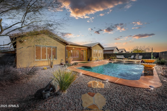 pool at dusk featuring pool water feature and a patio area