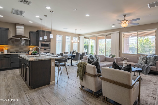 tiled living room featuring ceiling fan with notable chandelier and sink