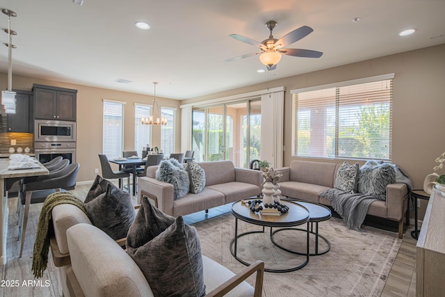 living room featuring plenty of natural light and ceiling fan with notable chandelier