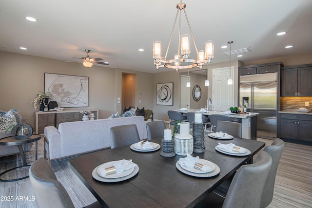 dining room with light hardwood / wood-style floors and ceiling fan with notable chandelier