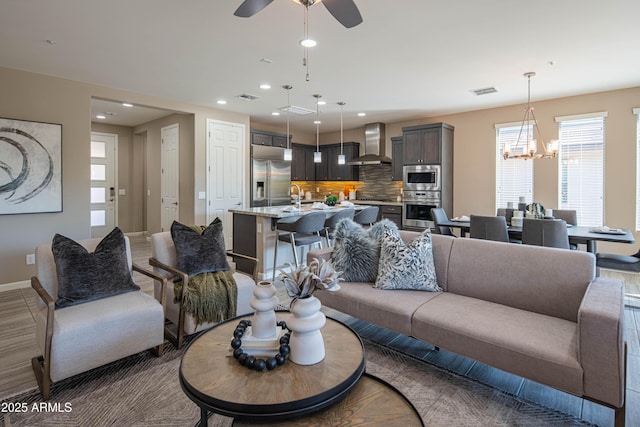 living room featuring ceiling fan with notable chandelier and sink