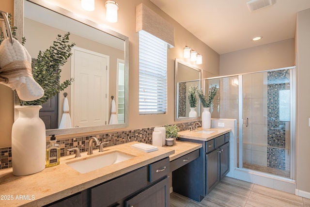 bathroom with a shower with shower door, vanity, and decorative backsplash