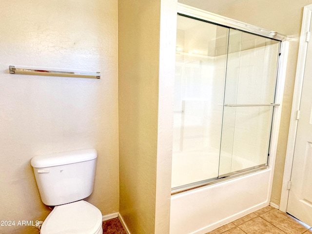 bathroom featuring shower / bath combination with glass door, tile patterned floors, and toilet