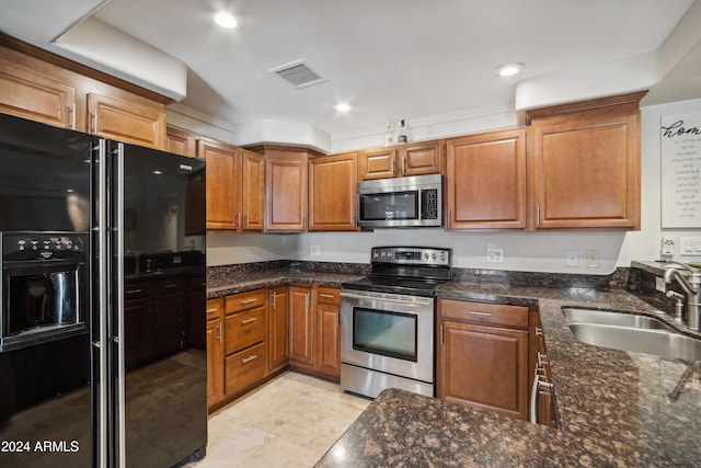 kitchen featuring dark stone countertops, appliances with stainless steel finishes, and sink