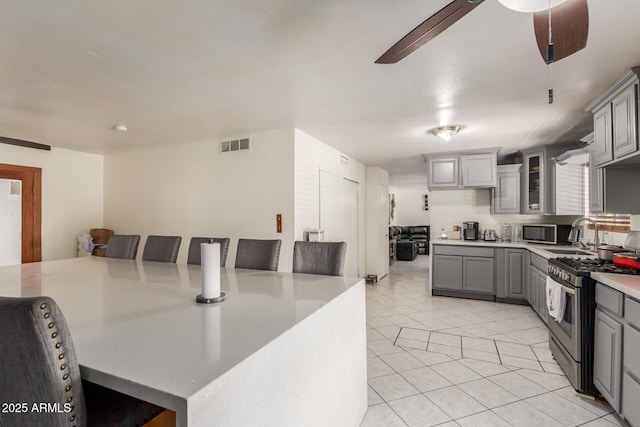2207 N 53rd Ave, Phoenix, AZ 85035 - kitchen featuring light countertops, gray cabinets, stainless steel appliances, light tile patterned floors, and visible vents