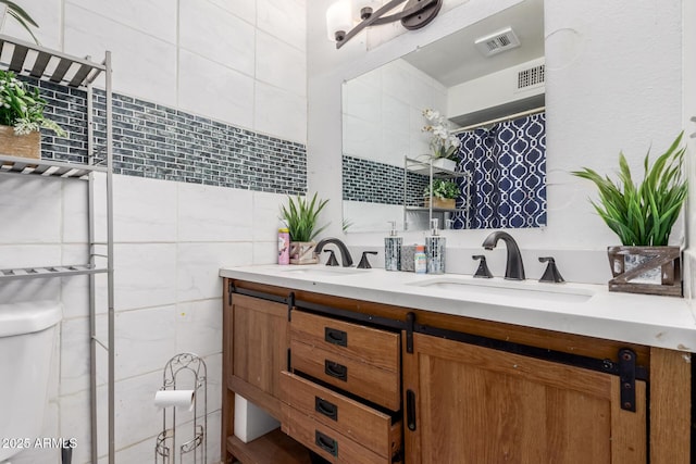 2207 N 53rd Ave, Phoenix, AZ 85035 - full bath with visible vents, a sink, double vanity, and tile walls