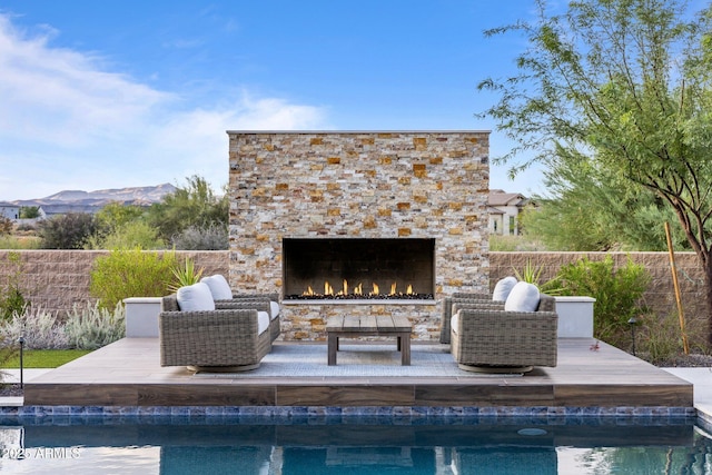 view of pool with a mountain view and an outdoor stone fireplace