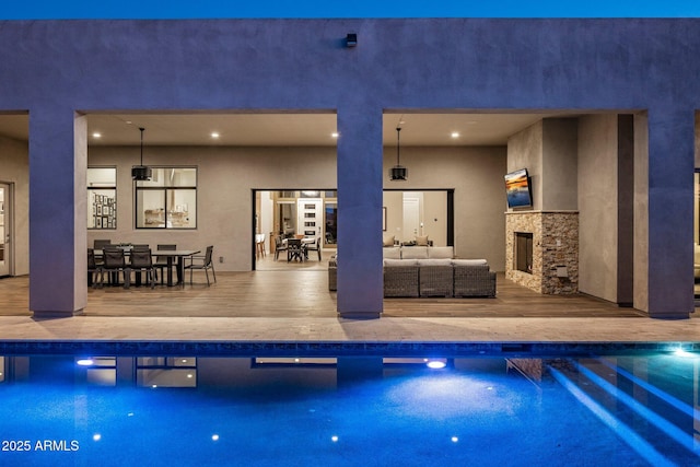 view of pool with an outdoor living space with a fireplace and a patio