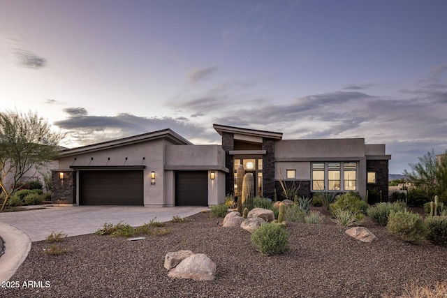 modern home featuring stone siding, an attached garage, and stucco siding