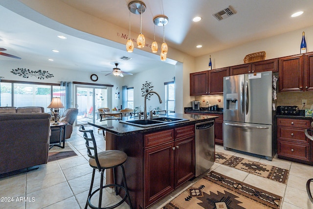 kitchen featuring tasteful backsplash, a breakfast bar, a center island with sink, sink, and appliances with stainless steel finishes