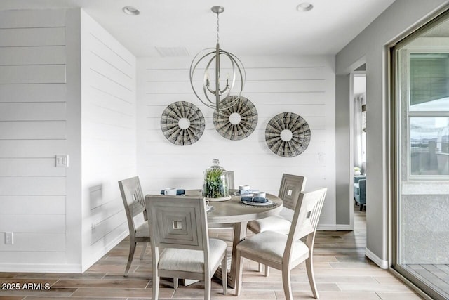 dining space with wood walls and an inviting chandelier