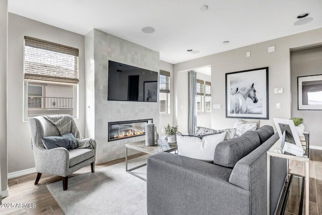 living room featuring a tiled fireplace and wood-type flooring