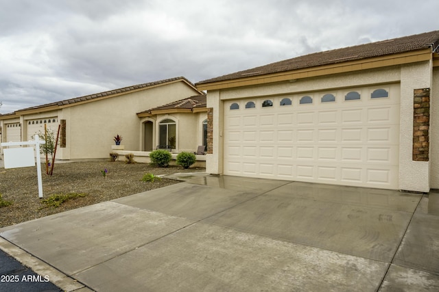 view of front facade featuring stucco siding, driveway, and a tile roof