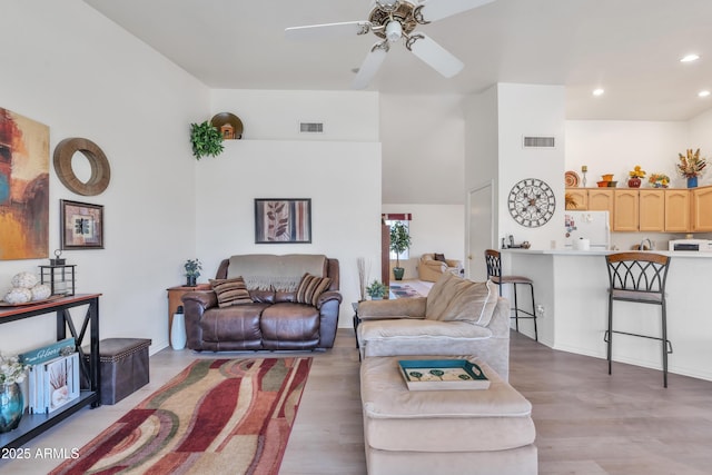 living room featuring hardwood / wood-style flooring, a towering ceiling, and ceiling fan