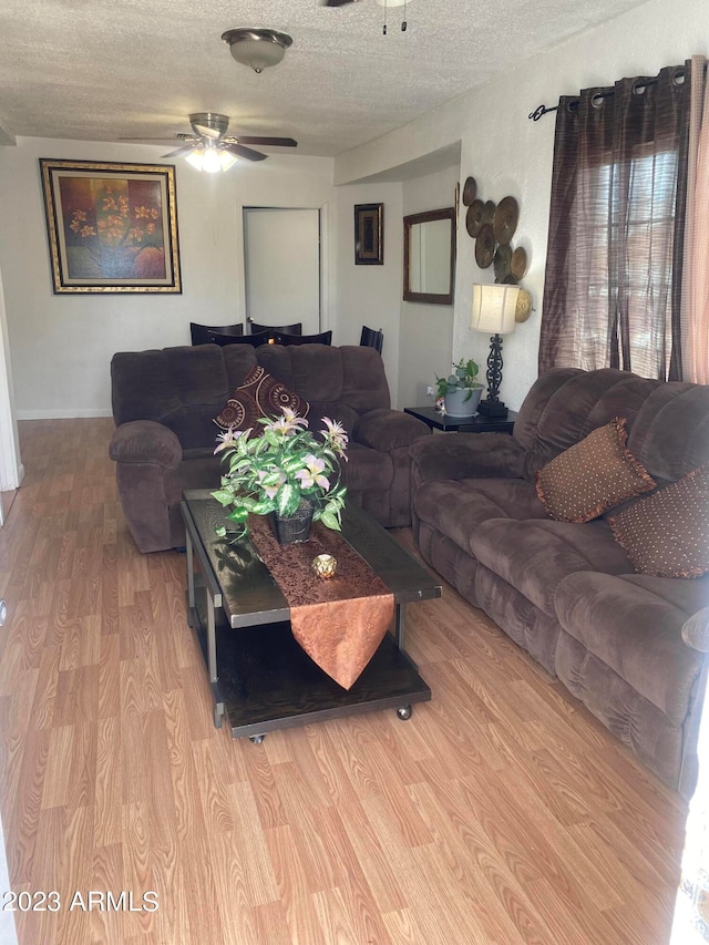 living room featuring ceiling fan, a textured ceiling, and light hardwood / wood-style floors