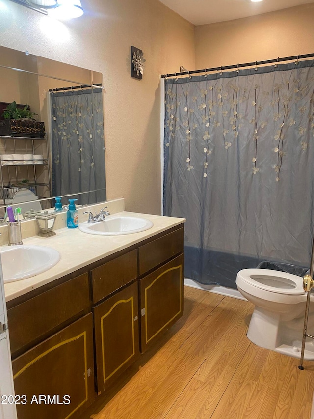 bathroom featuring double sink vanity, toilet, and hardwood / wood-style floors