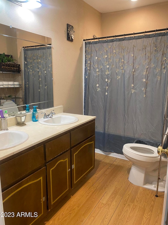 bathroom with dual sinks, oversized vanity, toilet, and hardwood / wood-style floors