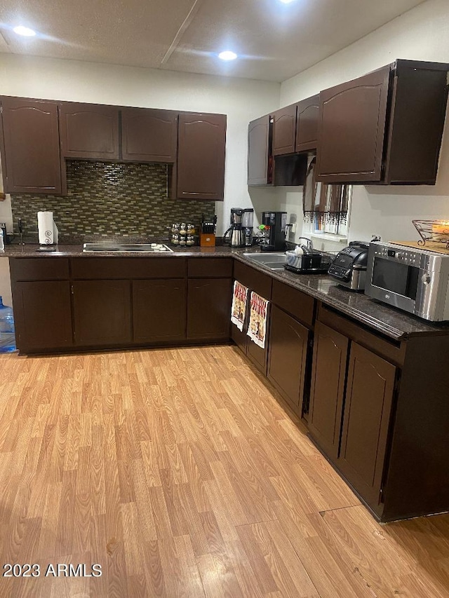 kitchen with dark brown cabinetry, tasteful backsplash, light wood-type flooring, and black electric stovetop