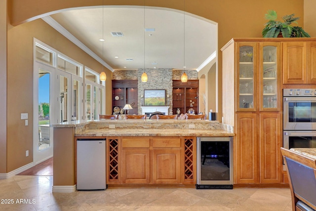 kitchen with refrigerator, ornamental molding, stainless steel double oven, light stone countertops, and beverage cooler