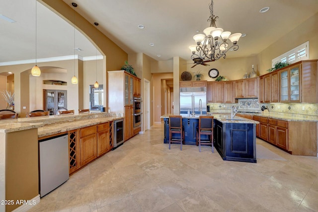 kitchen with wine cooler, built in refrigerator, fridge, backsplash, and a kitchen bar