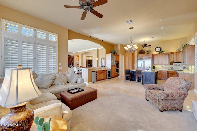 living room featuring arched walkways, visible vents, recessed lighting, and ceiling fan with notable chandelier