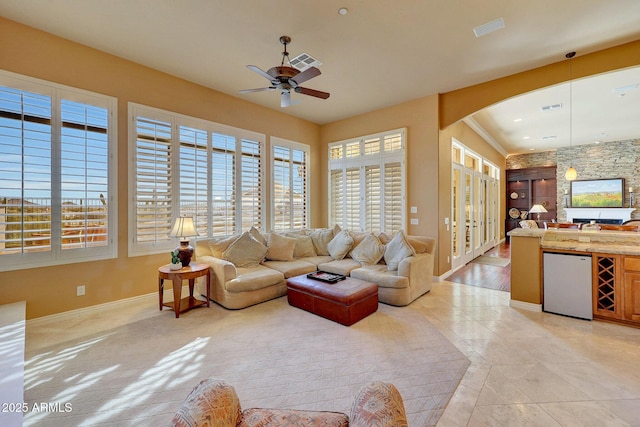 living room with ceiling fan, baseboards, visible vents, and arched walkways