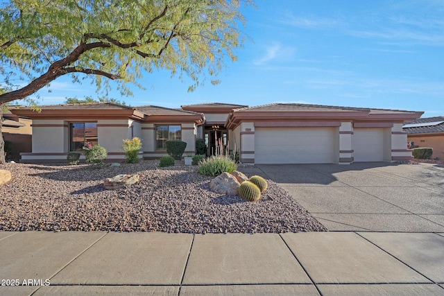 prairie-style house with driveway, an attached garage, and stucco siding