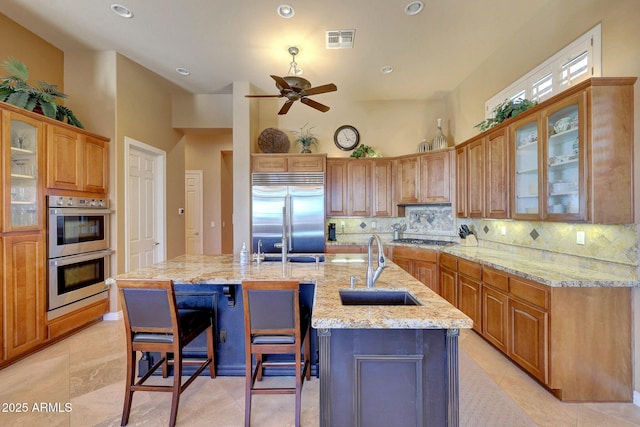 kitchen with appliances with stainless steel finishes, a sink, visible vents, and tasteful backsplash