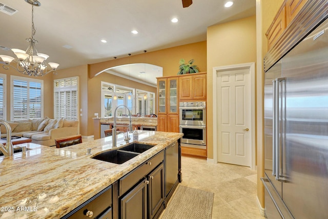 kitchen featuring a sink, visible vents, hanging light fixtures, appliances with stainless steel finishes, and light stone countertops