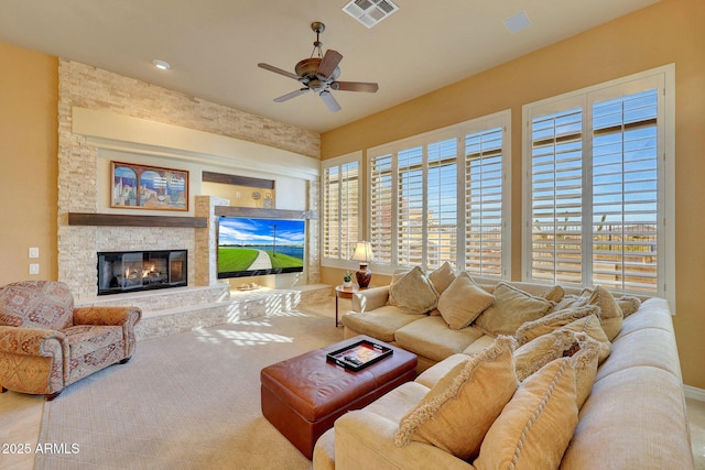 living area featuring a fireplace, visible vents, and a ceiling fan