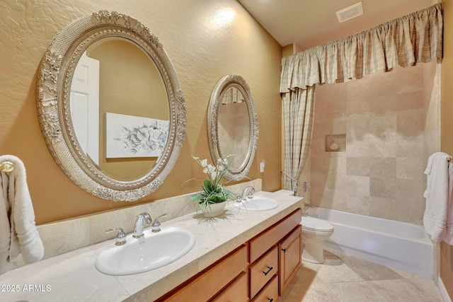 bathroom featuring toilet, double vanity, a sink, and visible vents