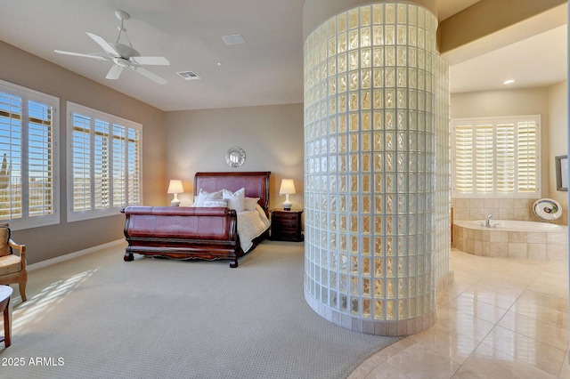 tiled bedroom featuring visible vents, ensuite bath, baseboards, and multiple windows