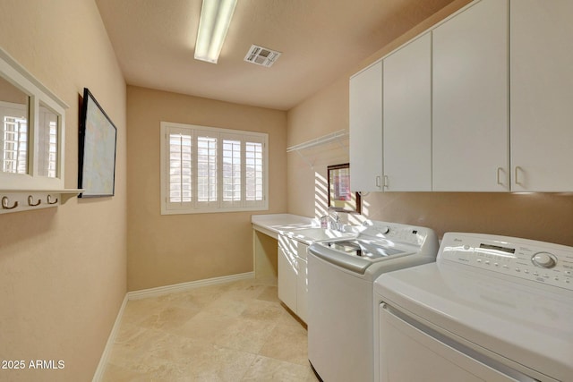 clothes washing area with washer and dryer, visible vents, cabinet space, and baseboards