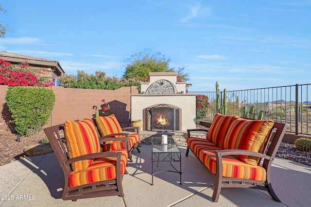 view of patio / terrace with fence and an outdoor living space with a fireplace