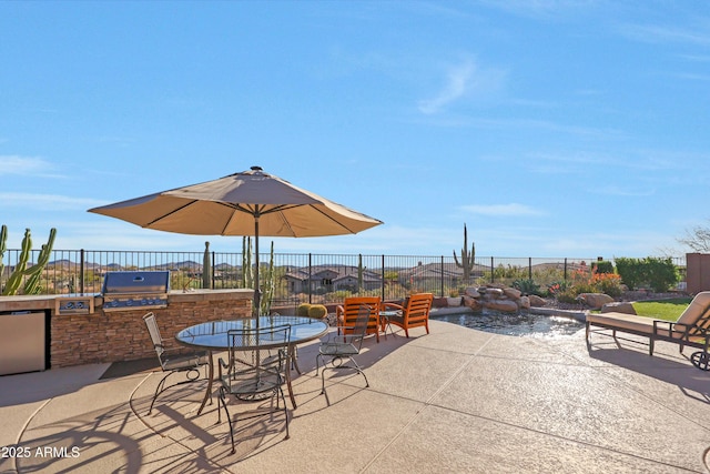 view of patio / terrace featuring outdoor dining area, a grill, fence, and an outdoor kitchen