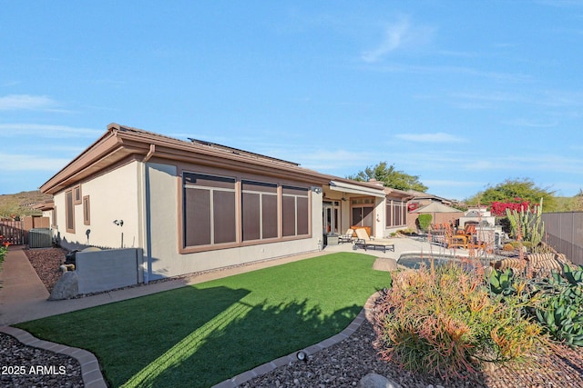 rear view of house featuring a yard, a fenced backyard, a patio, and stucco siding