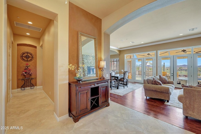 corridor featuring light wood finished floors, french doors, visible vents, and baseboards