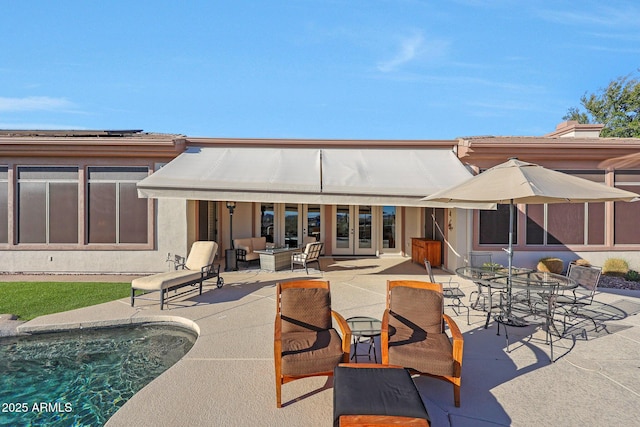 rear view of house featuring french doors, outdoor dining space, a patio area, and stucco siding