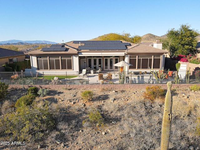 rear view of property with a mountain view, a chimney, a patio area, and a sunroom